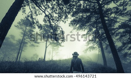 Grainy film style and vintage of man on dark misty forest path in fog for Halloween and horror concept 