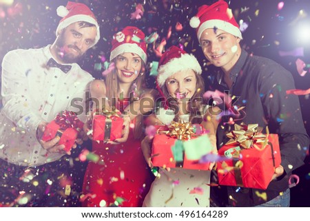Two couples having fun at New Year's party and holding nicely wrapped present boxes
