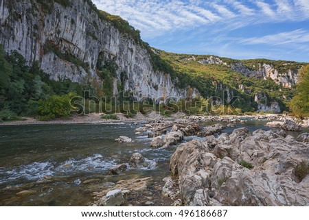 Mountain river with rapid current and driftwood caught on the rocks.
