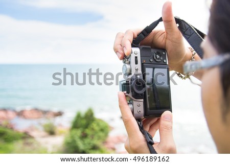 Hand holding a mirrorless digital camera for take a landscape photo