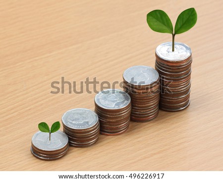 silver coin stack and treetop in business growth concept on wood floor.