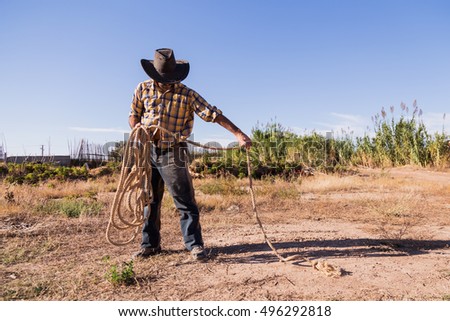 cowboy picking up a rope in the field
