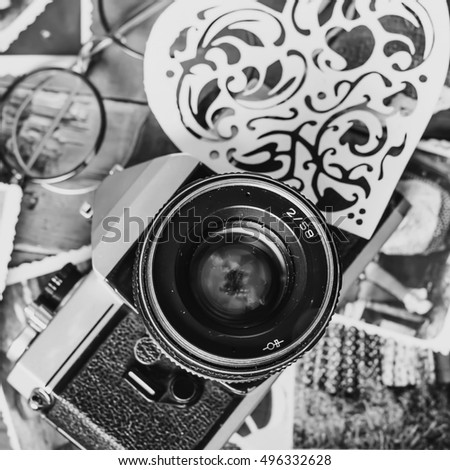 Old retro vintage camera, toy heart, bow tie, glasses, ring and book photography. Antique lens equipment. Black object photo. Classic creative background. Table image. Obsolete nostalgia style. 
