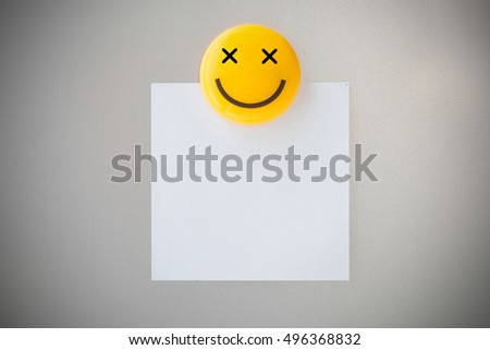 Plastic magnet clip on paper note on gray refrigerator background for input text.
