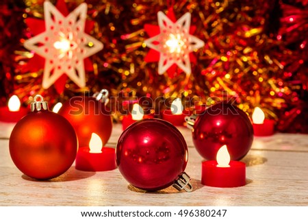 Christmas composition with red balls, stars and candles close up on a festive background of tinsel. Selective focus
