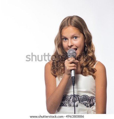 Emotional blonde girl in a white dress singing into a microphone on a white background