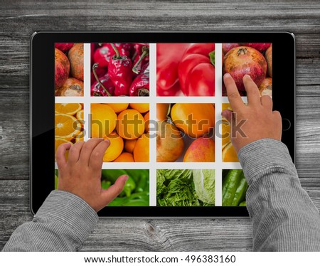 child hands touching  tablet computer screen with mixed fruit picture 