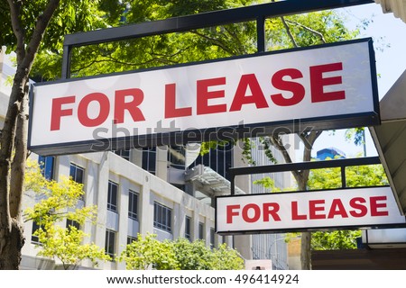 Two For Lease signs on display outside buildings during daytime