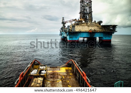 Anchor-handling Tug/Supply (AHTS)  vessel during dynamic positioning (DP) operations near Oil Rig. Royalty-Free Stock Photo #496421647