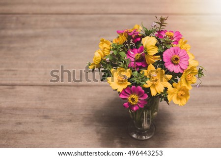 Bouquet of flowers on the old wooden table with vintage filter background.Selective Focus.