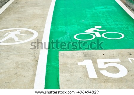 Signs, bike lane sign on green track and jogging on raw concrete beside