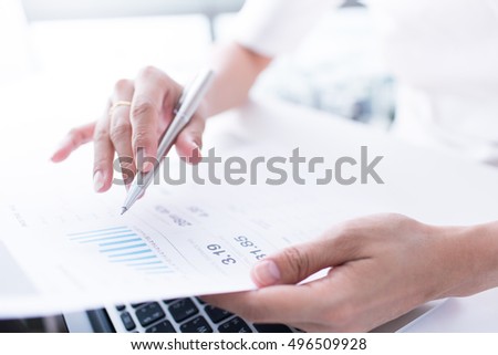 Young businesswoman reading paper at workplace