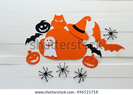 Cloud frame with ghost, pumpkins, spiders and bats cut out of paper. Happy Halloween card. Background of white wooden boards.