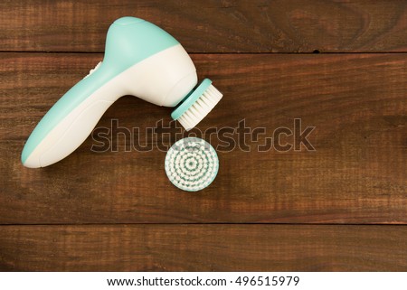 Electric brush cleanser on a wooden background.