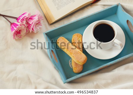 Image of romantic breakfast in the bed: cookies, hot coffee, flowers and open book