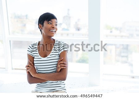 Portrait of a cheerful casual african businesswoman standing with arms folded in office