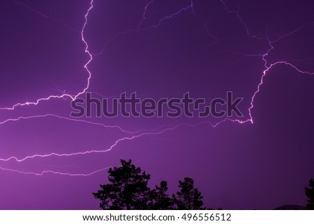 Lightning in the night sky above the treetops. Lightning Bolt Strike, storm.