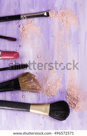 Makeup brushes and lipstick on a light purple background, with traces of powder and blush on it. A vertical template for a makeup artist's business card or flyer design, with copyspace