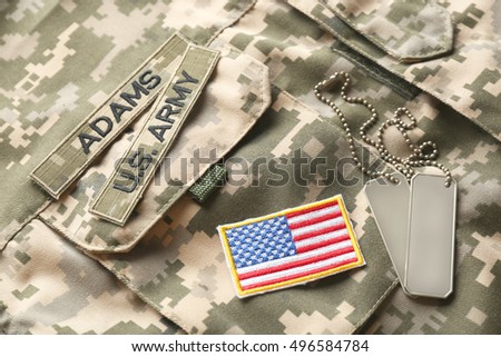 Soldier's tokens and little American flag on camouflage fabric background