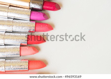 Row of wet lipsticks with copy space on beige background close up