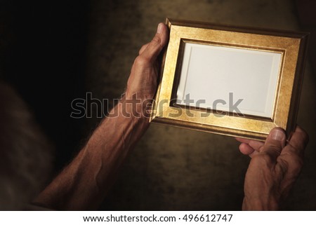 Old man holding and looking at photo frame