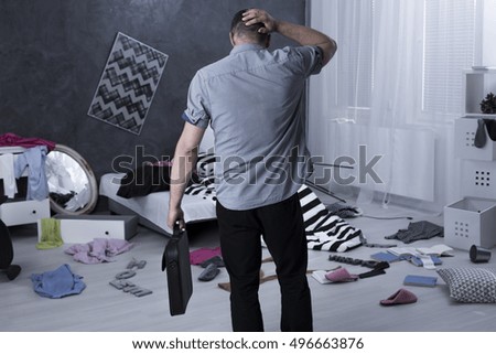 Man back view and chaos in apartment after burglary Royalty-Free Stock Photo #496663876