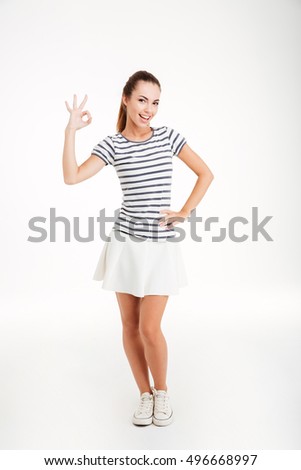 Full length portrait of a cheerful young girl showing ok sign with fingers isolated on the white background