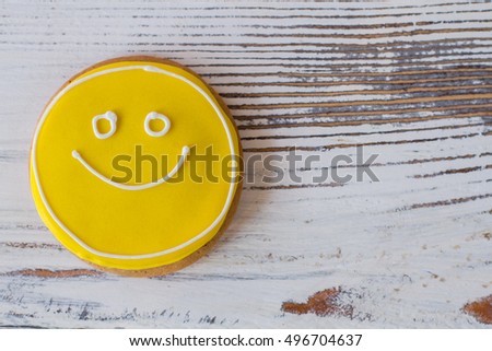 Smiley biscuit on wooden surface. Round cookie with icing. Charge of mood and energy. Don't forget to eat dessert.