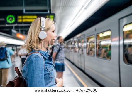 Young woman in denim shirt at the underground platform, waiting Royalty-Free Stock Photo #496729000