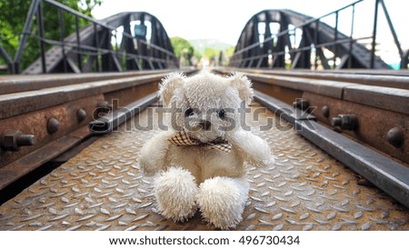 The little teddy bear travels to beautiful place, on steel railway bridge with clear blue sky