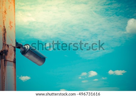 Security camera (CCTV) on blue sky and city background , process in vintage style