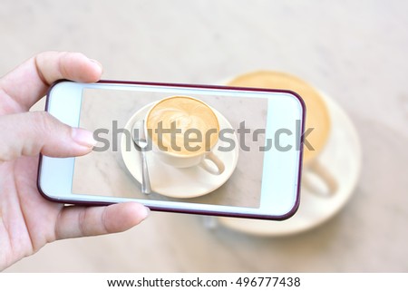 Women hand holding smartphone shooting hot coffee in coffee shop