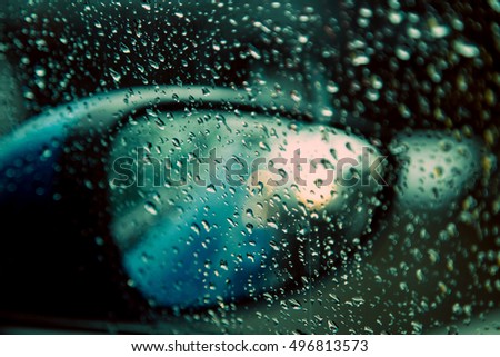 Raindrops on the car rearview mirror. Heavy rain outside/ Traffic and rain.