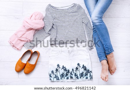 Fashion outfit and female legs on white wooden background. Top view and copy space.