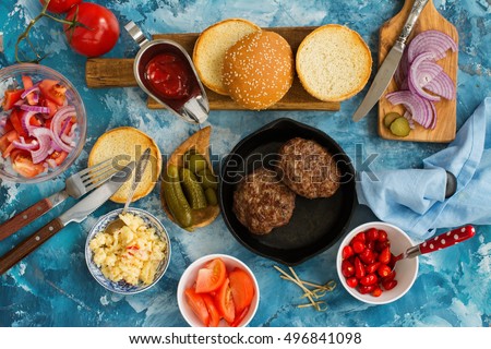 Preparing homemade burgers with beef cutlets, hot spicy scrambled eggs and vegetables. Top view. Space for text