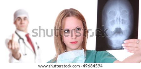 Beautiful young  female doctor holding up xrays with her medical assistant on background