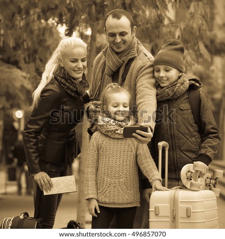 Traveling spanish spouses with children shooting mutual portrait on cell phone
