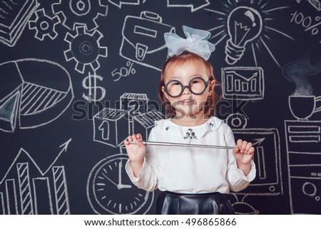 The little smart girl in glasses holding a pointer on dark background with business or school picture