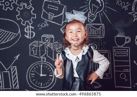 Little smart girl showing thumb up sign on dark background with business or school picture
