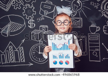 The little smart girl in glasses shows graphics company's activity on dark background with business or school picture