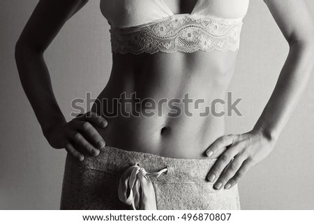 Fit woman's torso with her hands on hips close up. Female with perfect abdomen muscles on grey background. Dieting, fitness, active lifestyle concept