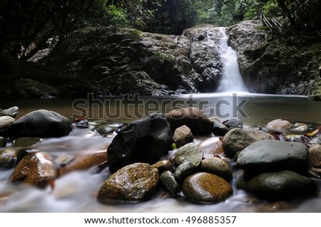 stream flowing among stones covered with plants and leaves, Water streams down moss covered rocks in Sekayu, Terengganu { slow shutter speed )