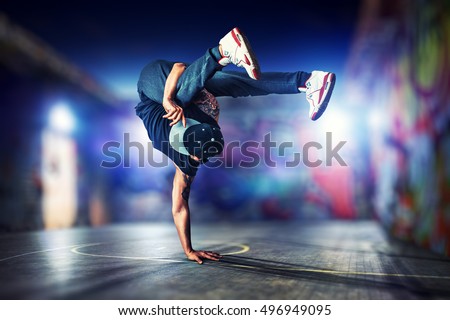 Young man break dancing at night on urban painted walls background Royalty-Free Stock Photo #496949095