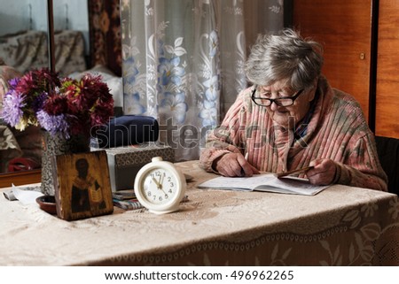 the grandmother reads at the table with glasses