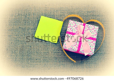 Wrapped gift with ribbon and love letter for Valentines Day, copy space for text on vintage tones