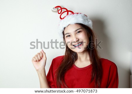 A beautiful young woman wearing santa hat and smiling on  white background.