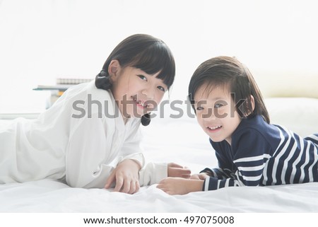 Cute asian children lying on white bed