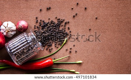 Scattered black pepper, onion, red chili pepper on wooden background flat lay top view