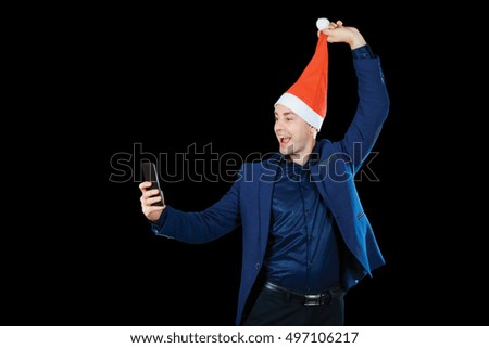Handsome young man in santa hat making selfie. Isolated on black