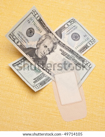 Money with a band aid on a yellow background to demonstrate the cost of health care.